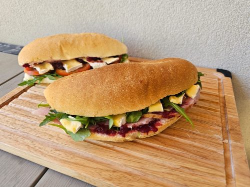 Our lunch catering package for Christmas 2025. Get these limited-edition lunch sandwich rolls for your corporate catering needs. Back left: Cranberry Brie Medley panini. Front centre: Christmas Ham & Brie panini. Delivers within Perth CBD and surrounding subrubs.